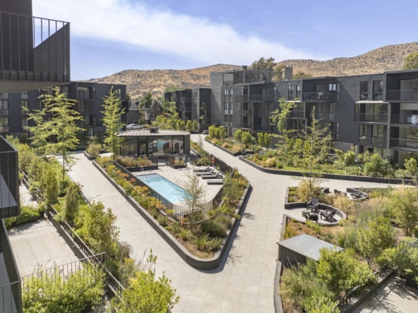 Render del condominio Mira Huechuraba mostrando edificios modernos, áreas verdes amplias, piscina central y vistas despejadas hacia la cordillera.